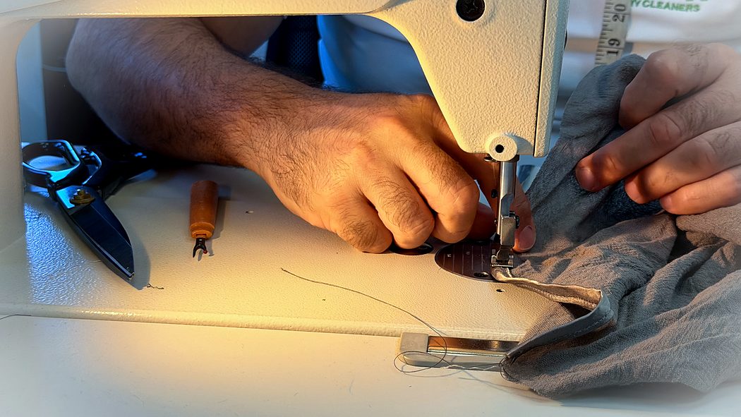 Hands guiding fabric under the needle on the industrial machine