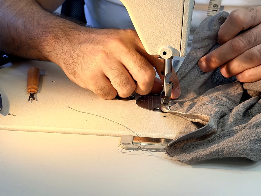 Our head of alterations guiding a garment under the needle on the industrial machine